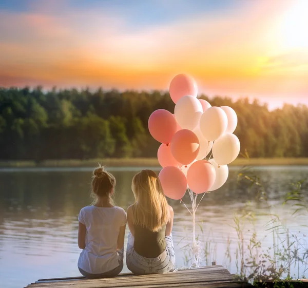 İki arkadaş (kız) göl kıyısı iskelede oturup...