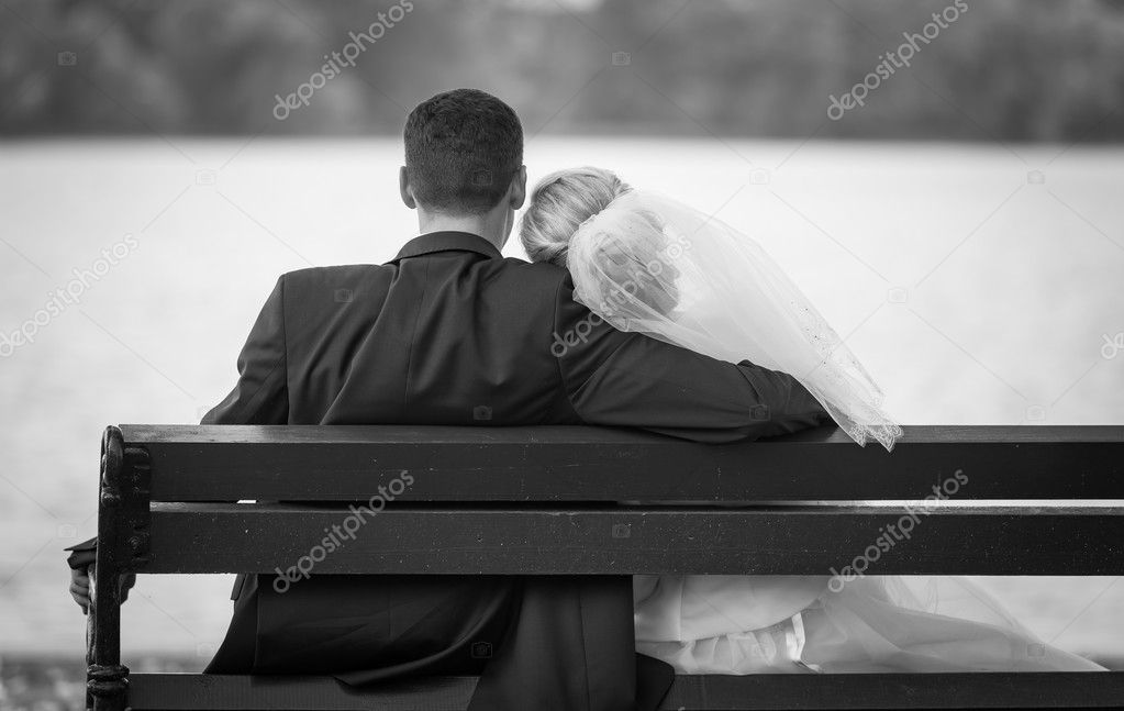 Wedding couple together sitting on park bench