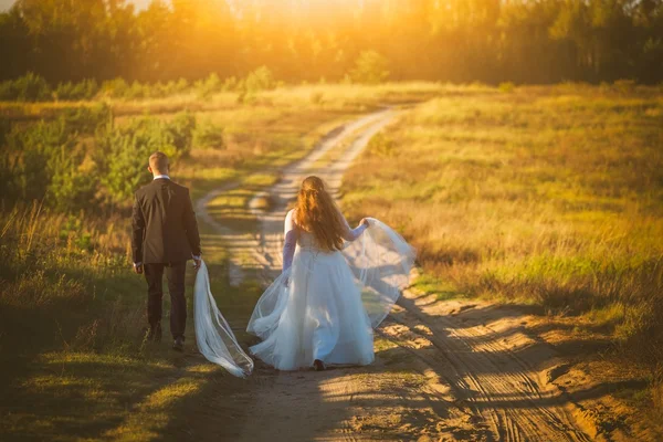 Casamento casal juntos andando por estrada arenosa na natureza — Fotografia de Stock