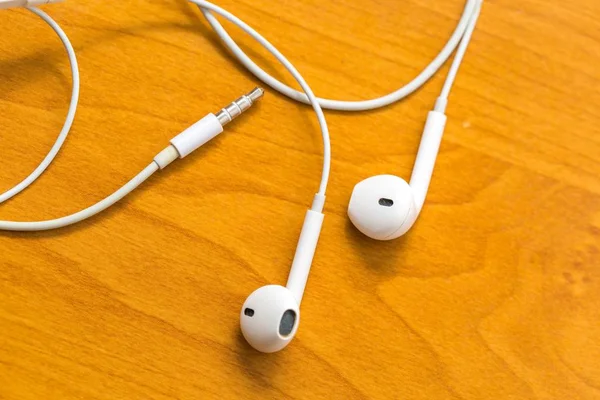 White headphones lying on wooden table