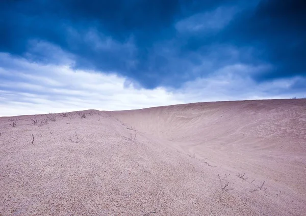 Sand dunes under cloudy sky at evening — Stock Photo, Image