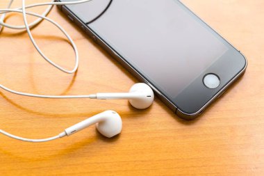 Ahşap masanın üzerinde yatan beyaz kulaklık