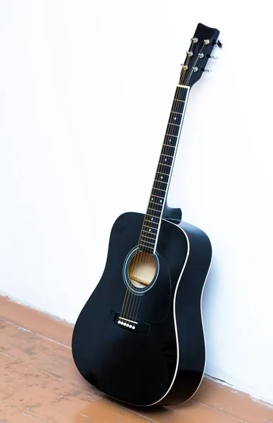Акустическая гитара рядом с белой стеной . — стоковое фото
