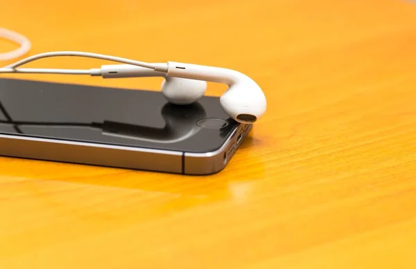 White headphones lying on wooden table — Stock Photo, Image