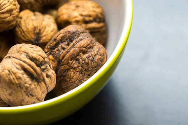 Walnuts in green ceramic bowl in close up. — Stock Photo, Image