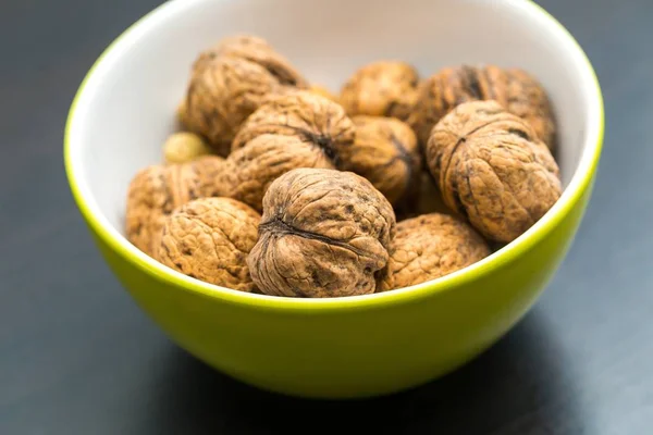 Walnuts in green ceramic bowl in close up. — Stock Photo, Image