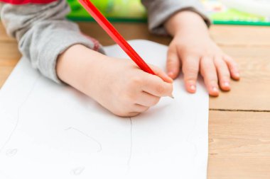 Küçük çocuk beyaz kağıt üzerine kalemle çizim