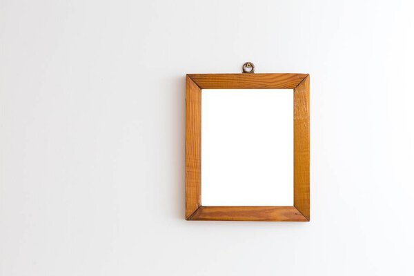 Old wooden frame of pine wood hanging on white wall background. Wooden frame on white wall.