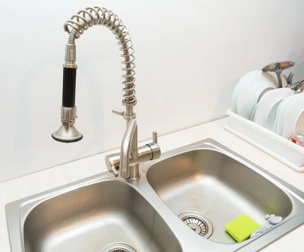 Close up of kitchen sink on white wall background.