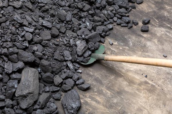 Черный уголь и лопата лежат на куче в подвале дома

