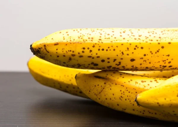 Manojo de plátanos acostados sobre una mesa de madera oscura — Foto de Stock