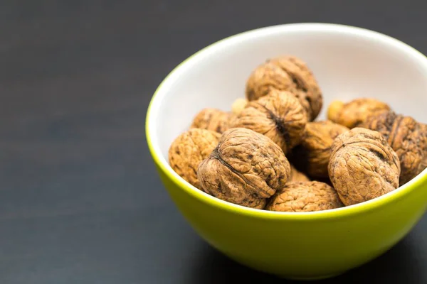 Walnuts in green ceramic bowl in close up. — Stock Photo, Image