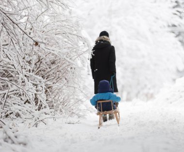 Anne küçük oğlu ile kızak çekme.
