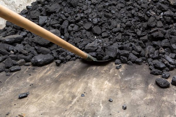 Black coal and shovel lying on a pile in house basement