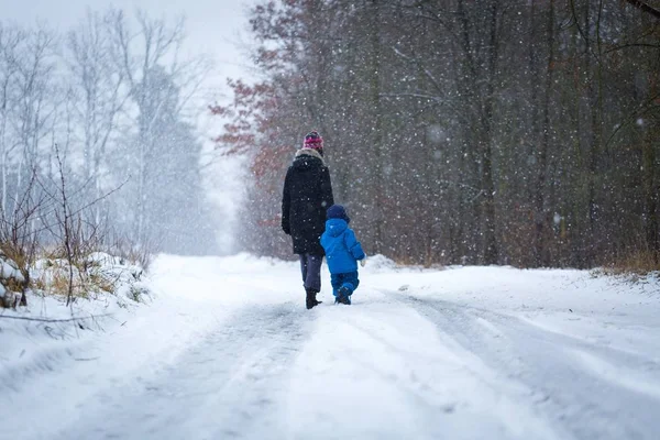 Madre e bambino a piedi da strada forestale sabbiosa in inverno — Foto Stock