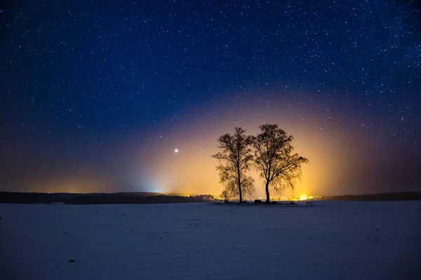 Vía Láctea y cielo estrellado sobre paisaje invernal y pueblo distante — Foto de Stock