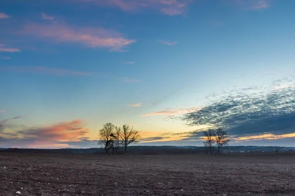 Céu colorido bonito do por do sol sobre o campo arado na primavera — Fotografia de Stock