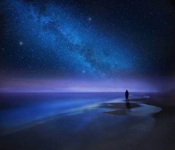 Cielo estrellado nocturno sobre mar y playa con silueta de hombre — Foto de Stock