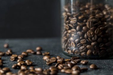Cam Kavanoz koyu arka plan üzerinde kahve çekirdekleri ile. Kahve yakın çekim.