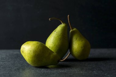 Yeşil armut koyu arka plan üzerinde yalan. Koyu zemin üzerine taze meyve.