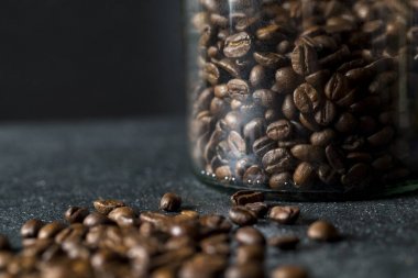 Cam Kavanoz koyu arka plan üzerinde kahve çekirdekleri ile. Kahve yakın çekim.
