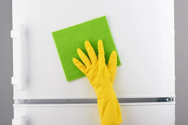 Hand in gelben Handschuh reinigt weißen Kühlschrank mit grünem Lappen — Stockfoto