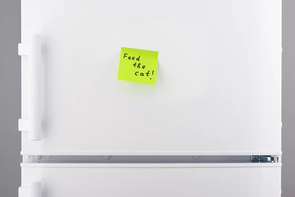 Накормите кошачью записку зеленой липкой бумагой на холодильнике — стоковое фото