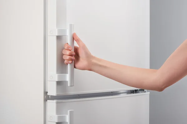 Female hand holding handle of white refrigerator door — Stock Photo, Image