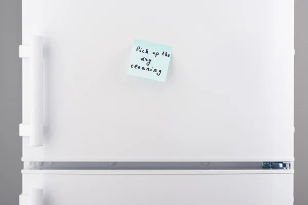 Pick up dry cleaning on blue notepaper on white refrigerator — Stock Photo, Image