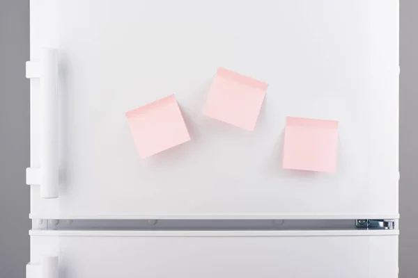 Τρεις κενό ελαφρύ ροζ χάρτινες κολλώδεις σημειώσεις σχετικά με ψυγείο λευκό — Φωτογραφία Αρχείου