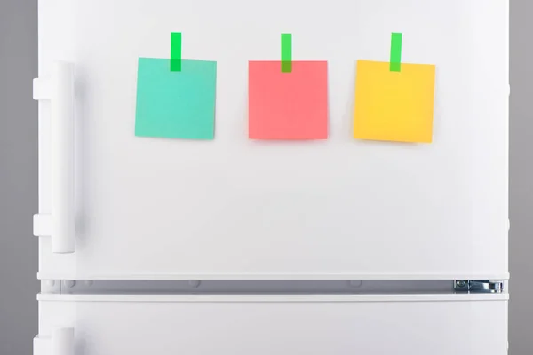Notas verdes, rosadas y amarillas pegadas con pegatinas en el refrigerador — Foto de Stock