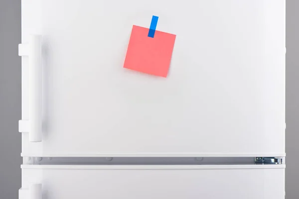 Ροζ χάρτινο Σημείωση συνημμένη με μπλε αυτοκόλλητο στο ψυγείο λευκό — Φωτογραφία Αρχείου