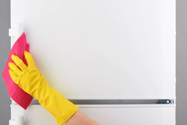 Hand in yellow glove cleaning white refrigerator with pink rag — Stock Photo, Image