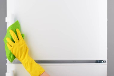 Sarı eldiven yeşil bez ile beyaz buzdolabı temizlik el