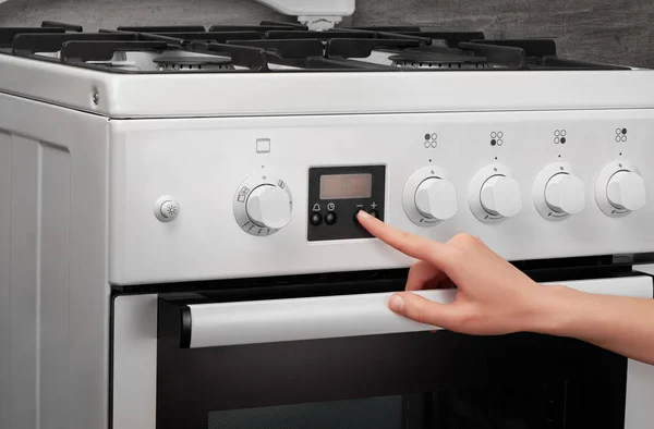 Female hand turning on white kitchen gas stove — Stock Photo, Image