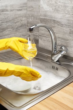 Hands in gloves washing wine glass under running tap water  clipart