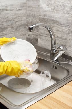 Ellerinde eldiven ile sünger Temizleme pembe beyaz tabak yıkama