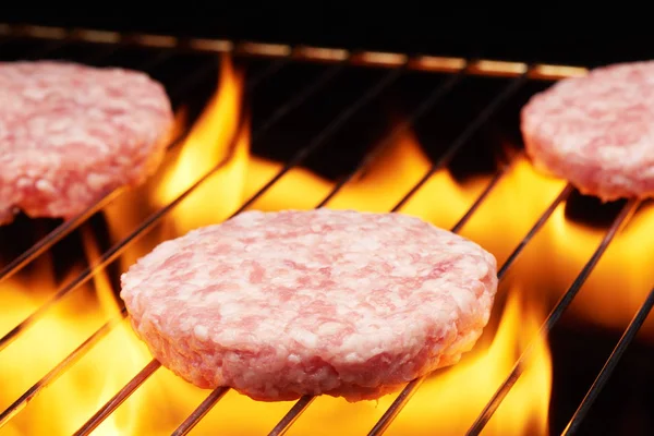 Hamburguesas crudas a la parrilla con llama —  Fotos de Stock