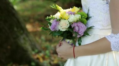 Güzel gelin buketi beyaz gelinliği giymiş genç gelinin elinde. Büyük eller taze beyaz gül ve Lale çiçekler demet kapatın. Anonim gelin holding çiçekler