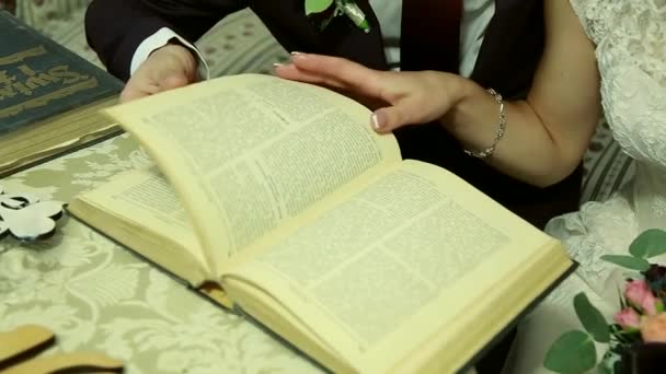 Рука поклала два обручки на книгу, створюючи серцеві тіні — стокове відео