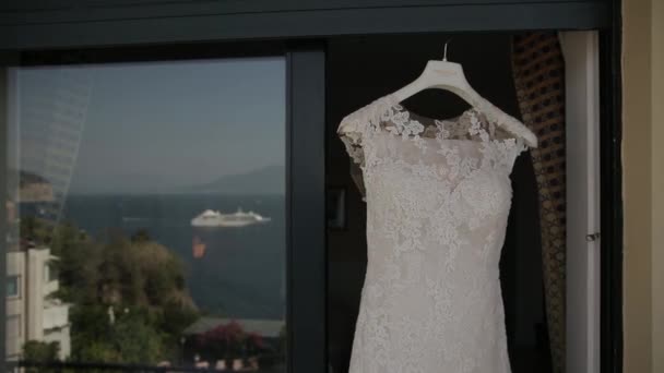 Свадебное платье висит в дверях, на заднем плане — стоковое видео