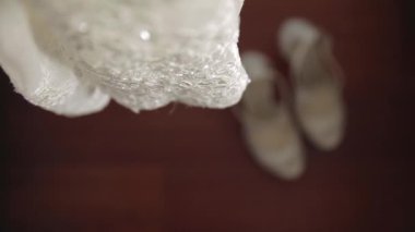 Gelin beyaz düğün ayakkabıları elleriyle giyer.