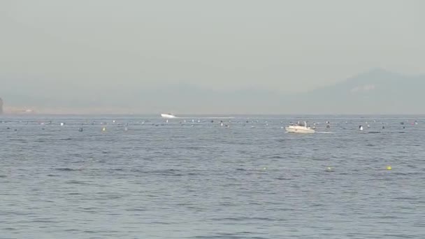 Маленький човен, що пливе уздовж моря, на тлі острова з горами — стокове відео