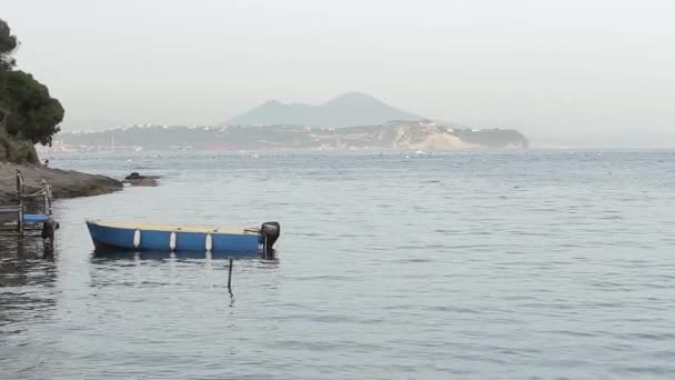 Un pequeño barco navegando a lo largo del mar, en el fondo de una isla con montañas — Vídeo de stock