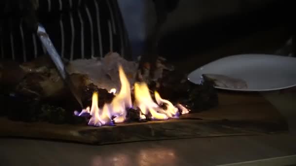 Kocken skär köttet som fortfarande brinner — Stockvideo