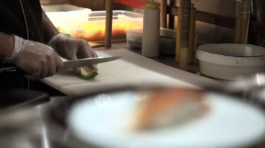 Suşi rulo yapma işlemi. Adam kadar yeşil rite avokado dilimleri tarafından kesme. Hazırlanan suşi rulo tutulur geçmesine