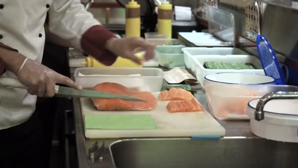 Process of making and cutting salmon for sushi rolls. Cook cutting up fish by knife on thin slices. — ストック動画