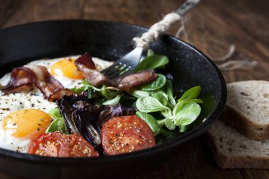 Kahvaltı Seti. Pastırmalı kızarmış yumurta, domates ahşap arka plan üzerinde Pan