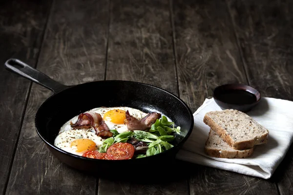Завтрак готов. Пан из жареных яиц с беконом, помидор на деревянном фоне — стоковое фото