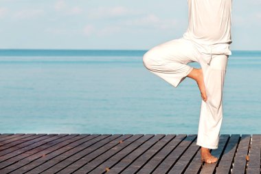 Adam beyaz giysili ahşap iskele yoga meditasyon